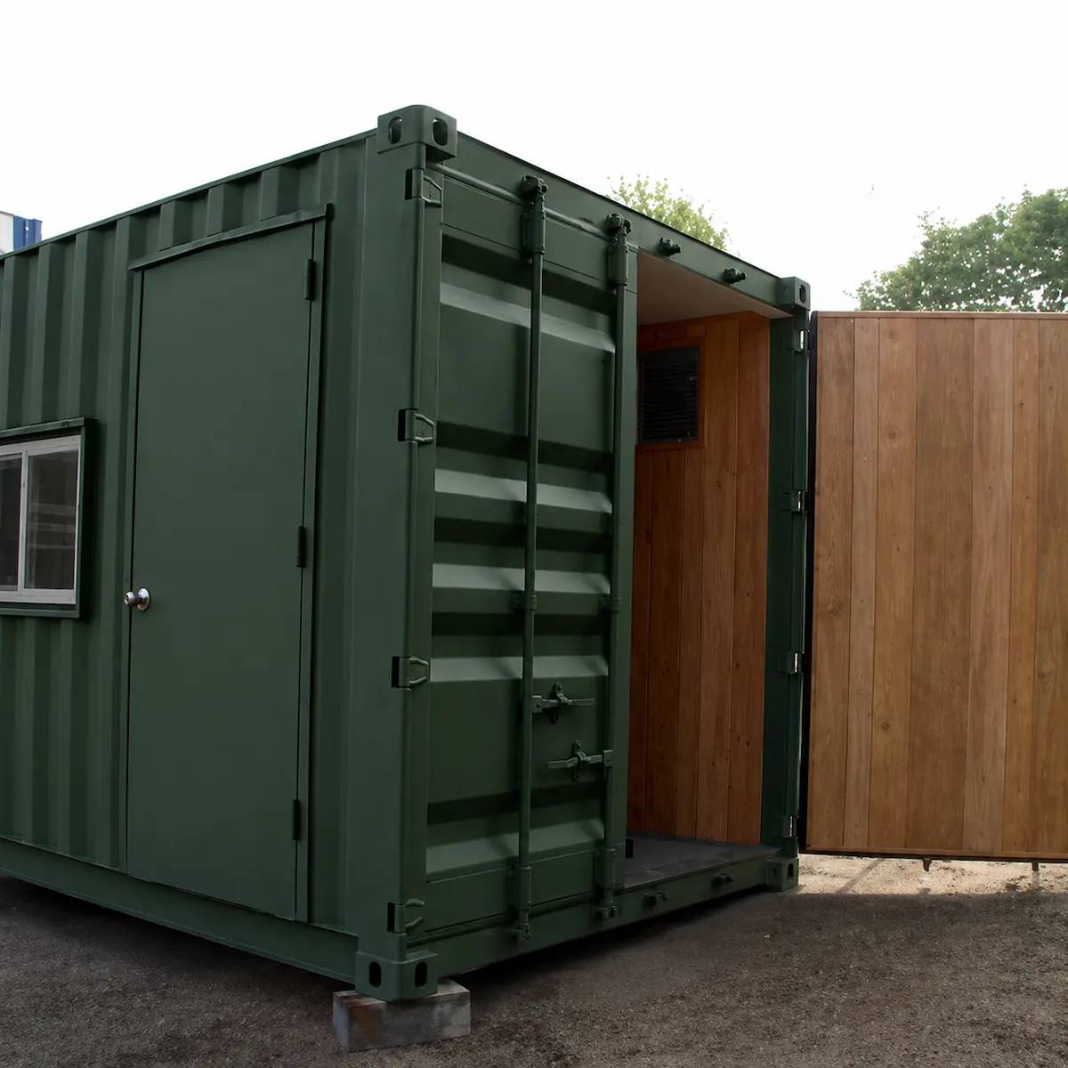 Green modified shipping container office with cargo doors, personnel access door, timber-lined interior, and sliding window, ideal for portable site offices, storage, and workspace applications.