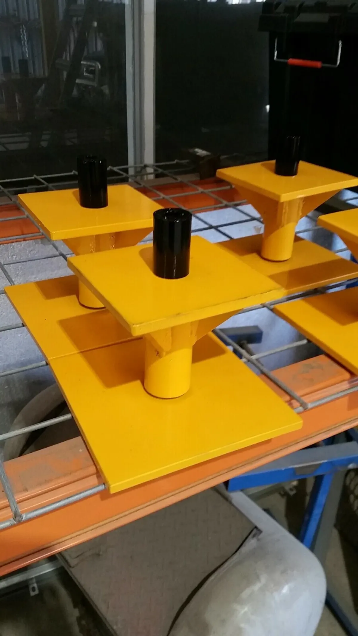 Shipping container stands — yellow steel corner stands with black ISO twist lock pins, set of four, workshop setting